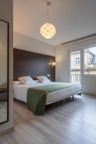 a bedroom with a large bed and a large window at Hotel Mendez Nuñez in Lugo