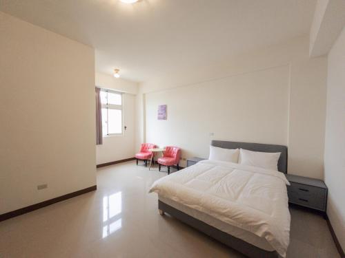 a bedroom with a white bed and two red chairs at Yearning Homestay in Taitung City