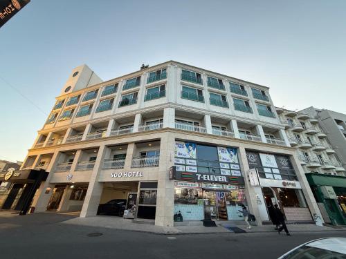 a tall building on a city street with people walking in front at Gyeongpo Soo Hotel in Gangneung