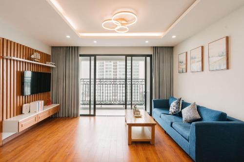 a living room with a blue couch and a tv at D Le Roi Soleil Premium Suites in Hanoi