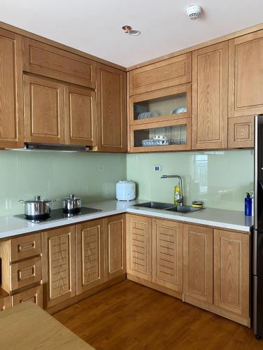 a kitchen with wooden cabinets and a sink at D Le Roi Soleil Premium Suites in Hanoi
