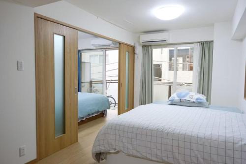 a white bedroom with a bed and a window at 位于新桥的2卧室公寓 in Tokyo