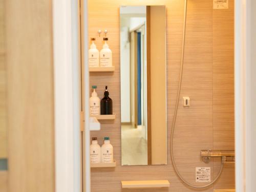 a bathroom with a shower with a mirror and bottles at 位于新桥的2卧室公寓 in Tokyo