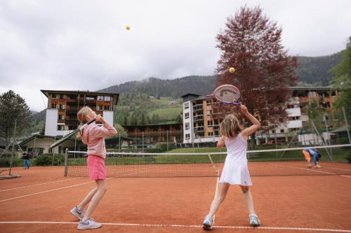 two people playing tennis on a tennis court at Hotel Die Post in Bad Kleinkirchheim