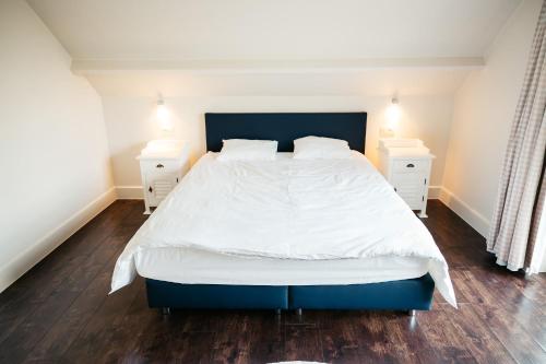 a bedroom with a large white bed and two night stands at B&B Anna-Grace in Diksmuide