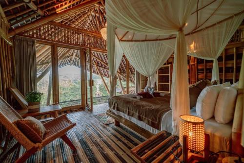 a bedroom with a bed in a room with windows at CR Tris Casa De Bambú in Selat