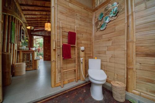 a bathroom with a toilet in a wooden wall at CR Tris Casa De Bambú in Selat