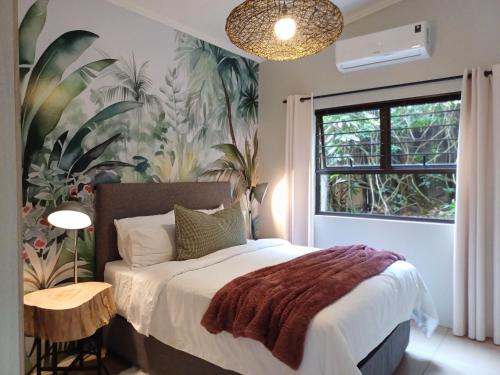 ein Schlafzimmer mit einem Bett mit tropischer Tapete in der Unterkunft Buckingham Cottage in Pinetown
