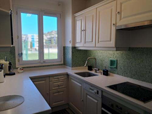 une cuisine avec des armoires blanches, un évier et une fenêtre dans l'établissement LES MOUETTES A, à Cannes