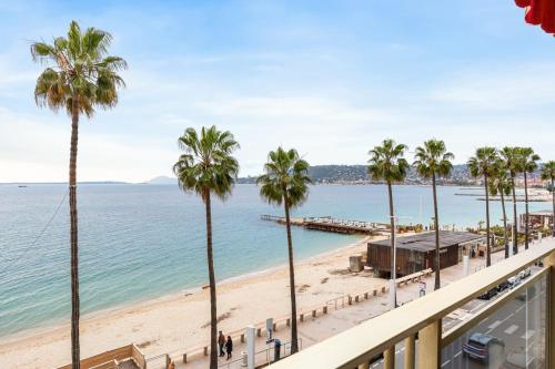 une vue sur une plage avec des palmiers et l'océan dans l'établissement Suite Bleu Vue Mer Confort à Juan-les-Pins, à Antibes