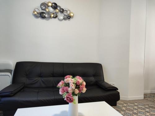 a black couch in a living room with a vase with flowers at Entire home - Centre Fécamp - 45 Rosa in Fécamp