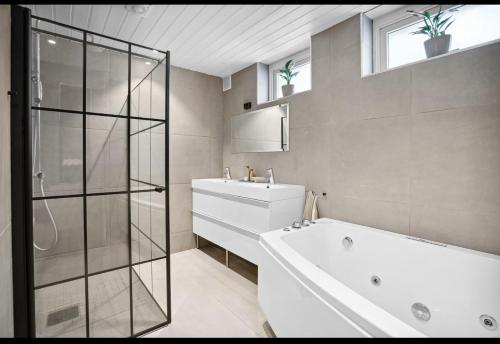 a bathroom with a tub and a sink and a shower at Rom i Leilighet nærheten av Gardemoen Norway, 15C Østli in Elstad
