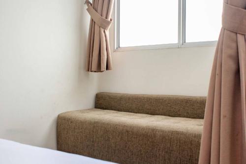 a couch sitting under a window in a room at Simple and Comfort Studio at Riverview Jababeka Apartment By Travelio in Cikarang