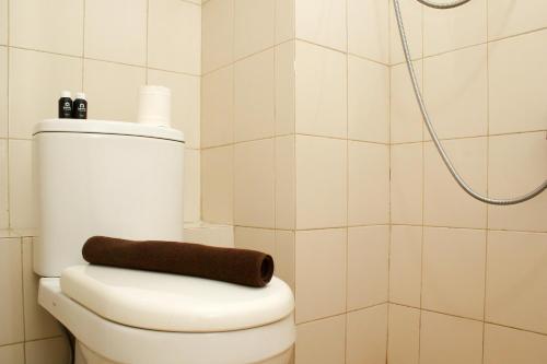 a bathroom with a toilet with a brown towel on it at Simple and Comfort Studio at Riverview Jababeka Apartment By Travelio in Cikarang