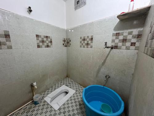 a bathroom with a toilet and a blue bucket at VN Guest House in Prayagraj
