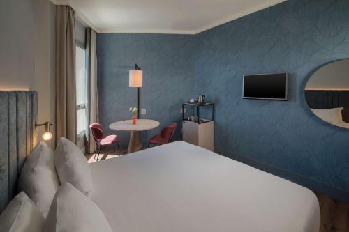 a hotel room with a large bed and a table at NH La Spezia in La Spezia