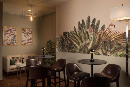 a waiting room with tables and chairs and a painting on the wall at NH La Spezia in La Spezia