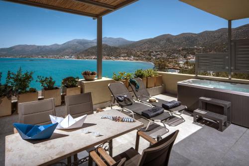 a patio with a table and chairs and a view of the water at Skajado Holiday Apartments in Stalida