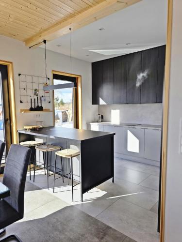 a kitchen with a black island and some chairs at Czôrny Dąb - nowoczesny dom wakacyjny na Kaszubach, jacuzzi, sauna, bilard in Garcz