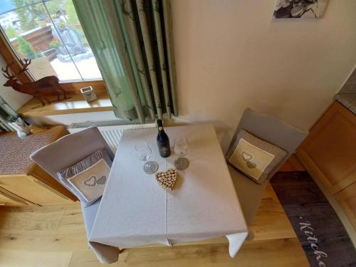 a table with a bottle of wine and two chairs at Ferienwohnung Landhaus Lechner in Buchau
