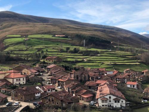 a village with houses and a green field on a hill at El Molino de Leyte - Charming Riverside Cottage in Carmona, Cantabria in Carmona