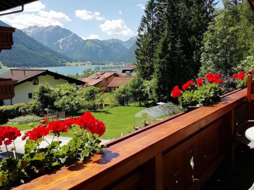 a balcony with red flowers and a view of a lake at Ferienwohnung Landhaus Lechner in Buchau