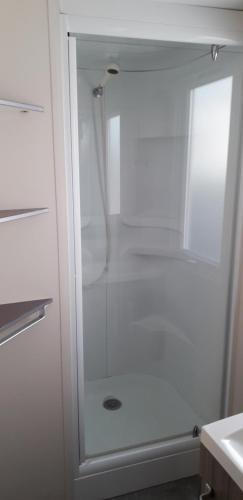 y baño con ducha blanca y puerta de cristal. en omer novela, en Port-la-Nouvelle