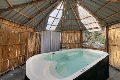 a large bath tub in a hut with a window at Echor Palm Bliss Riverside Resort & Spa Kasol in Kasol