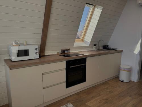 a kitchen with a counter with a microwave and a sink at Air Cabin, Cabana tip A-frame in Șerani, Bihor in Şerani