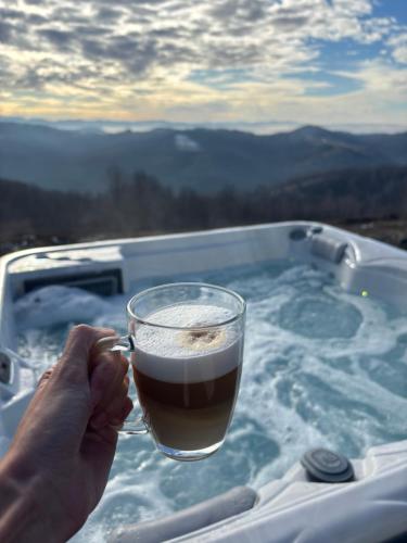 a person holding a glass of beer in a hot tub at Air Cabin, Cabana tip A-frame in Șerani, Bihor in Şerani