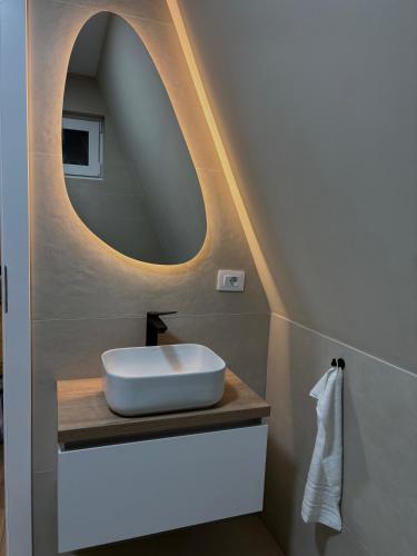 a bathroom with a sink and a round mirror at Air Cabin, Cabana tip A-frame in Șerani, Bihor in Şerani