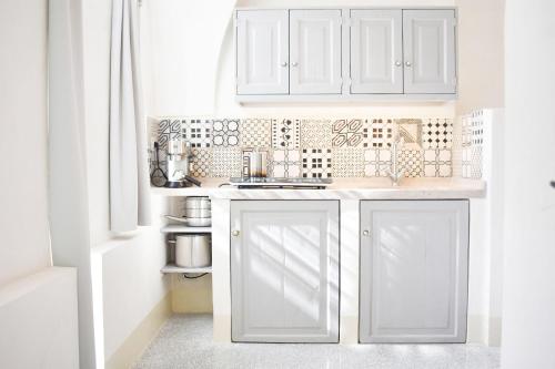 a white kitchen with white cabinets and a sink at Masseria Alchimia in Fasano