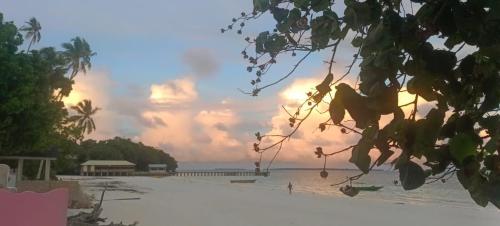a view of a beach with a sunset in the background at Noel Cottage in Ngurblut