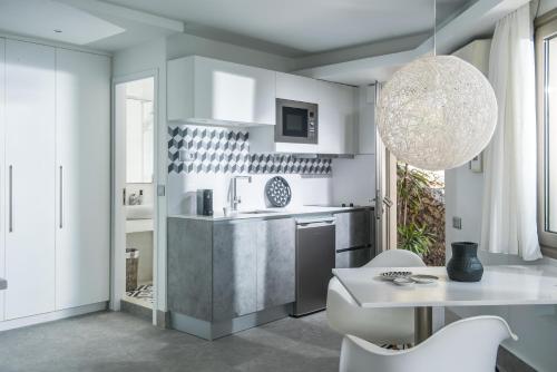 a kitchen with white cabinets and a table and chairs at Skajado Holiday Apartments in Stalida