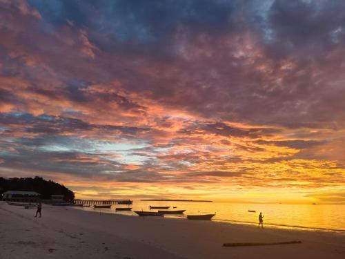 a group of boats on the beach at sunset at Noel Cottage in Ngurblut