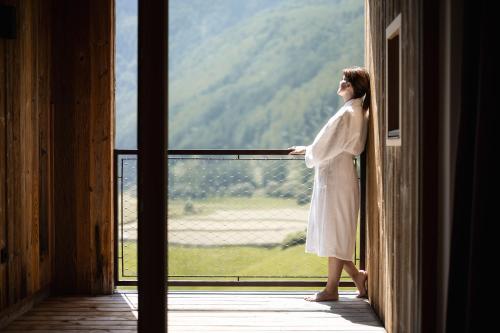 a woman standing on a porch looking out a window at Tonzhaus Hotel in Senales