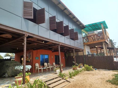 a house with a balcony and tables and chairs at Adinam's Beach Retreat in Nyanyanu
