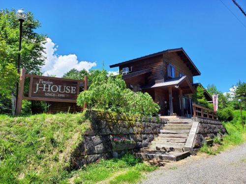 a wooden house with stairs in front of it at Pension J-HOUSE in Kiso
