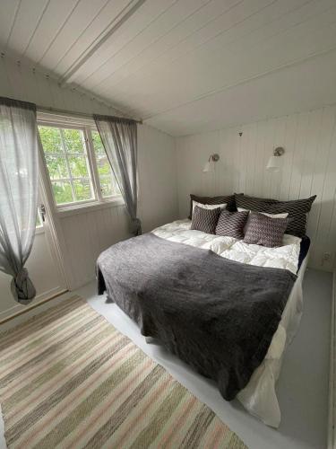 ein Schlafzimmer mit großem Bett und Fenster in der Unterkunft Cozy cottage in Stockholm Archipelago! in Muskö