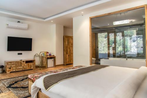a bedroom with a bed and a tv on the wall at Echor Palm Bliss Riverside Resort & Spa Kasol in Kasol