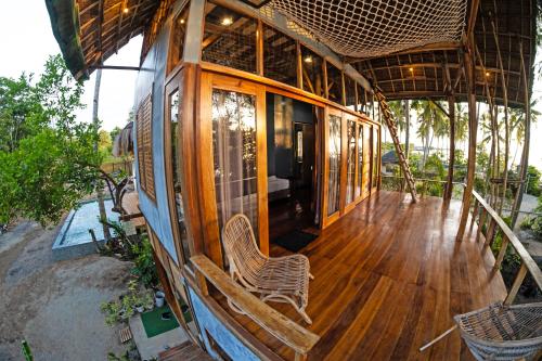 a house with a wooden deck with two chairs on it at Angeles Hut Fishermans Wharf in Laguindingan
