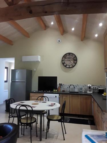 une cuisine avec une table et des chaises et une horloge au mur dans l'établissement La Longère des Basses Terres, à La Garnache