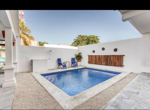 a swimming pool in a house with two blue chairs at Hotel Yukon in Playa del Carmen
