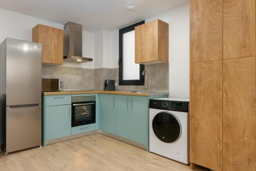 a kitchen with blue cabinets and a washer and dryer at Live It Malaga in Málaga