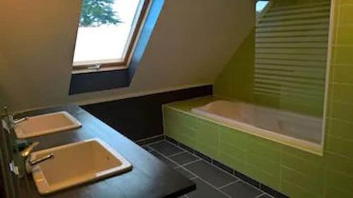 La salle de bains verte est pourvue d'un lavabo et d'une baignoire. dans l'établissement Maison et Plage de Sable Fin, à l'Île-Tudy