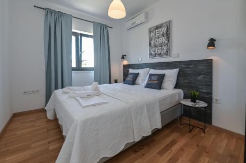a bedroom with a large white bed with a wooden floor at Pool Villa Vistamar in Novalja