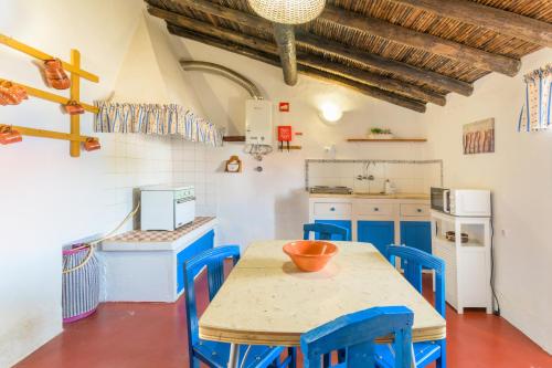 a kitchen with a wooden table and blue chairs at Herdade Vale de Gaios in Odemira