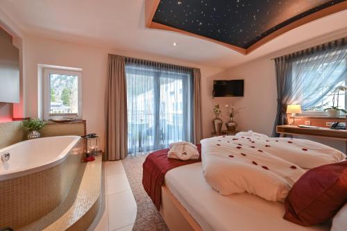 a bedroom with a large bed and a bath tub at Villa Ludwig Suite Hotel in Hohenschwangau