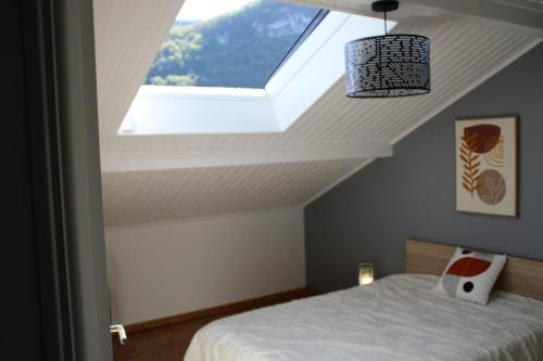 une chambre avec un lit et une lucarne dans l'établissement Villa des 3 fontaines, à Annecy