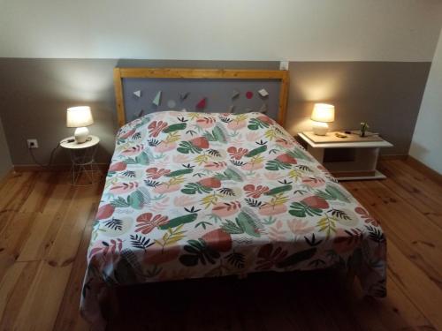 a bedroom with a bed with a floral bedspread and two lamps at Laroclya in Lilhac